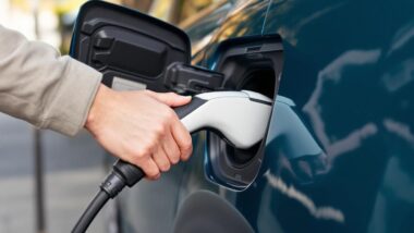 Main branchant un câble de charge sur une voiture électrique