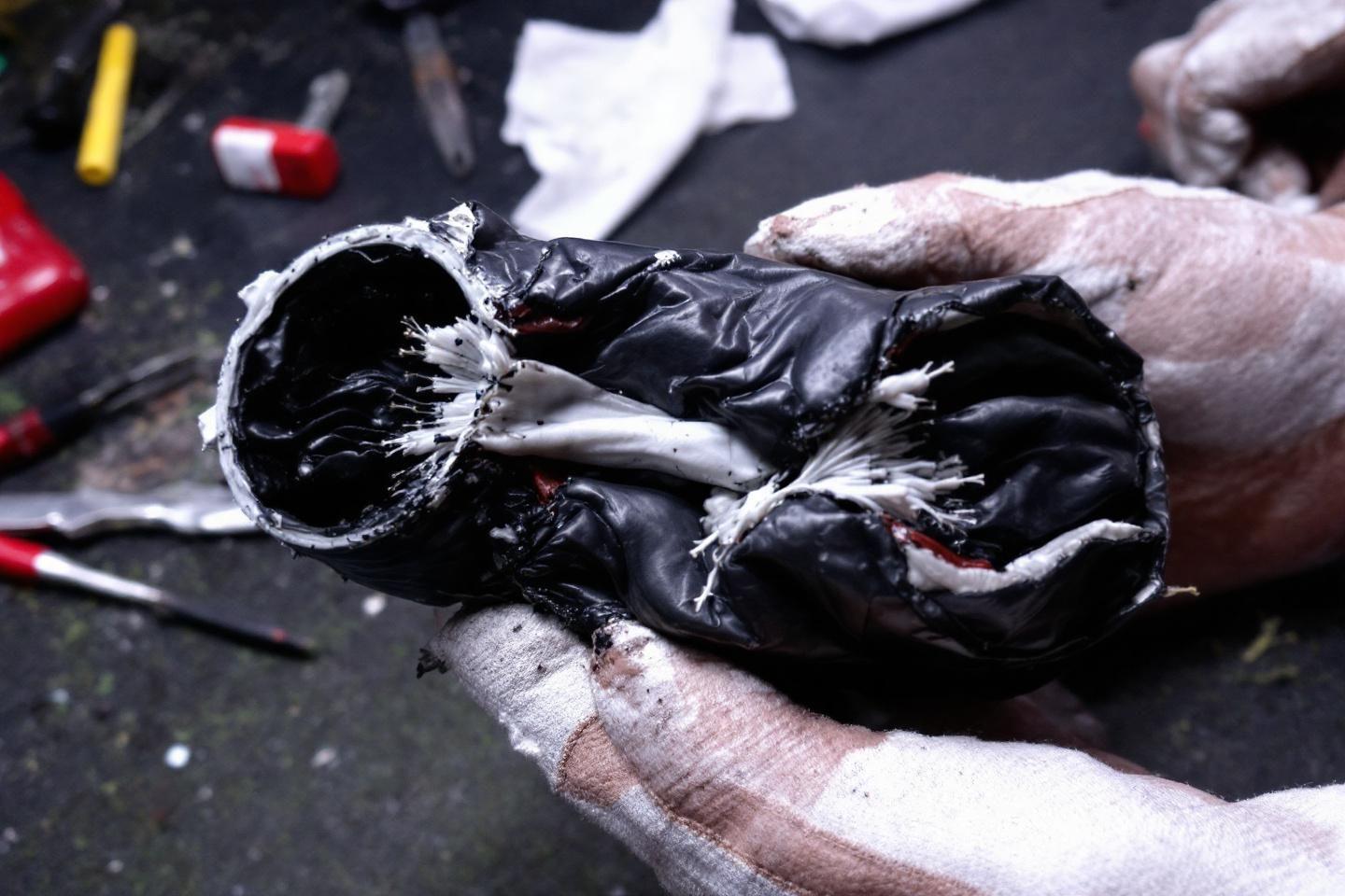 Gant noir déchiré et abîmé tenu par une main gantée