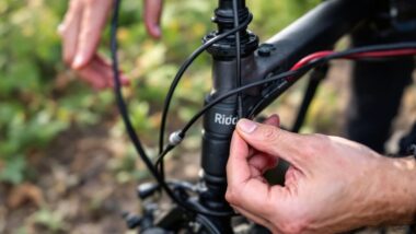 Mains ajustant le guidon d'un vélo noir dans la nature