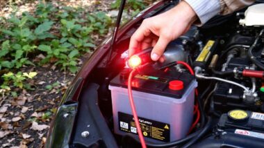 Main testant une batterie de voiture avec des câbles rouges